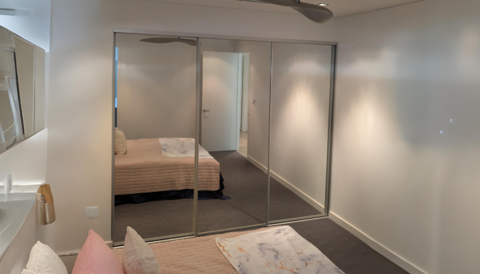 Bedroom with mirrored Glass Sliding Robes and white walls