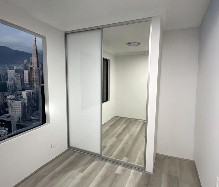 Bedroom with frosted and mirrored Glass Sliding Robes, wood floor